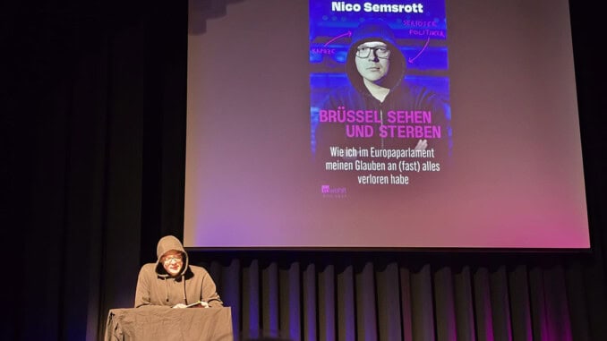Nico Semsrott liest auf einer Bühne aus seinem Buch vor